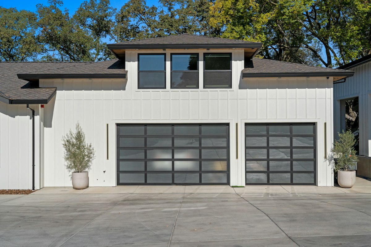 Deux portes de garage vitrées à cadre noir sur une façade blanche