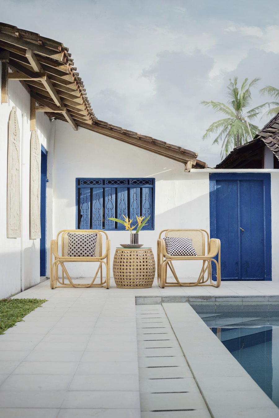Deux fauteuils en rotin et une table d’appoint au bord d’une piscine